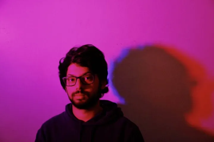 Steff in front of a magenta wall, his shadow split into blue and red